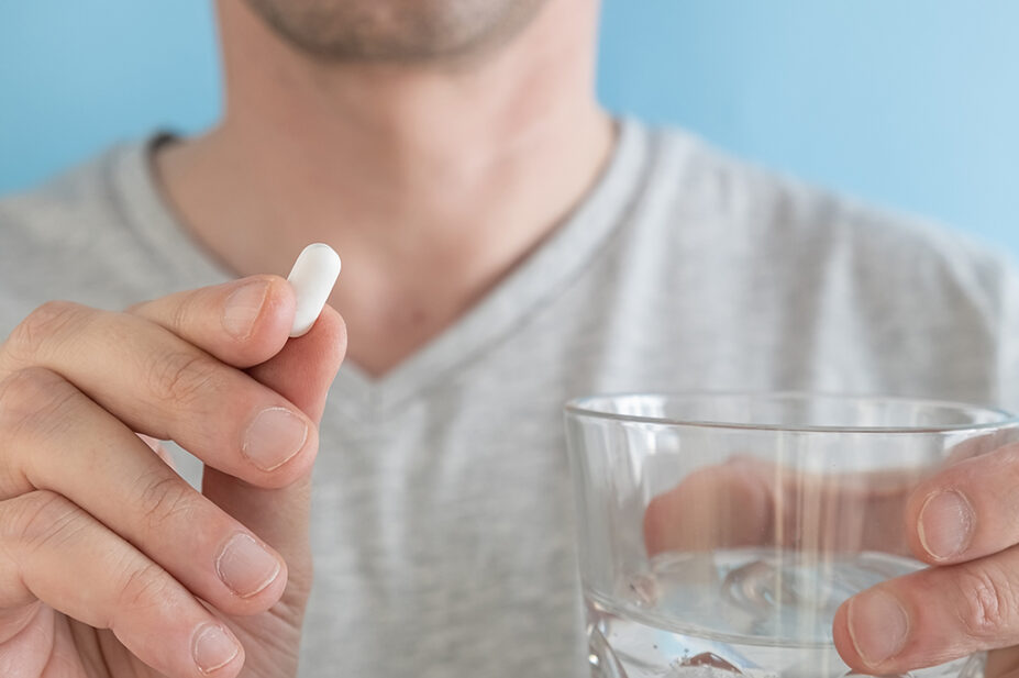 Man taking tablet with glass of water