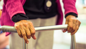 Older woman walking with frame in care home setting