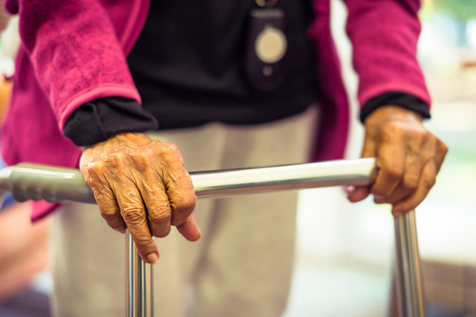 Older woman walking with frame in care home setting