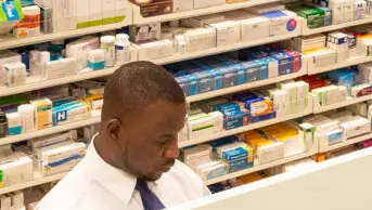 Pharmacist standing behind pharmacy counter