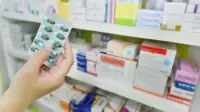 Packets of medicines in a dispensary, with hand holding blister pack of pills