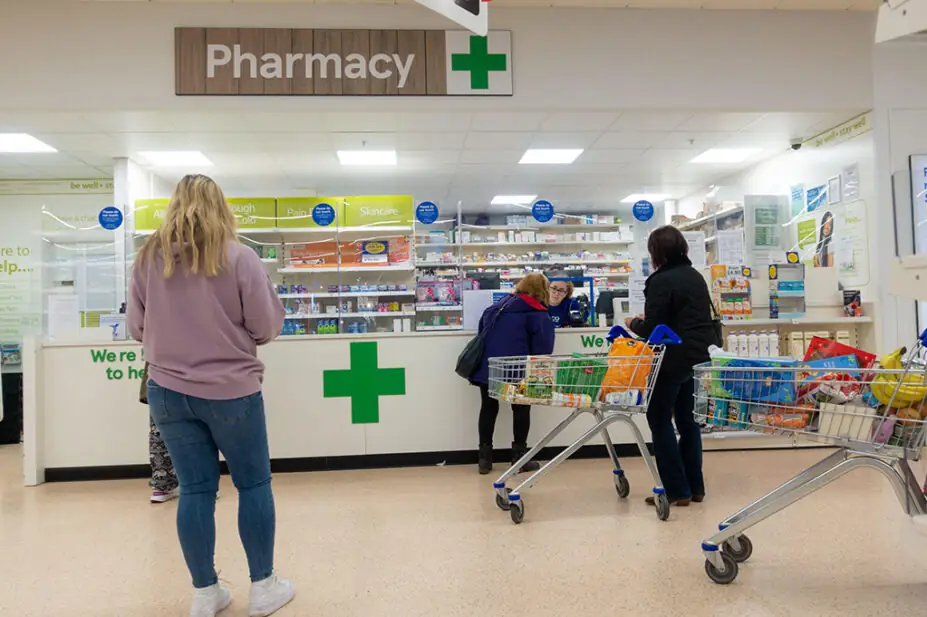 Customers queuing at a Tesco pharmacy counter