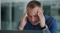 Man clutching his head in pain in an office