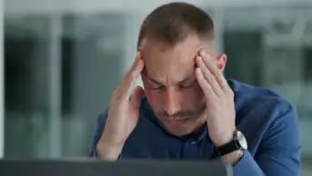 Man clutching his head in pain in an office