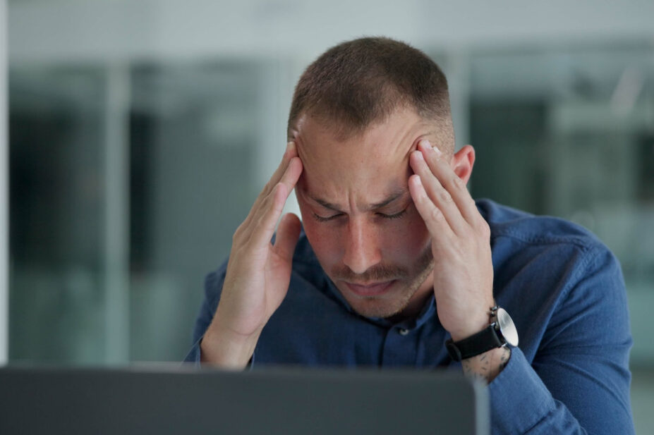 Man clutching his head in pain in an office