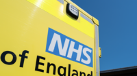 The rear of an ambulance displaying the NHS England logo