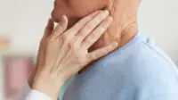 Clinician checking someone's throat and neck