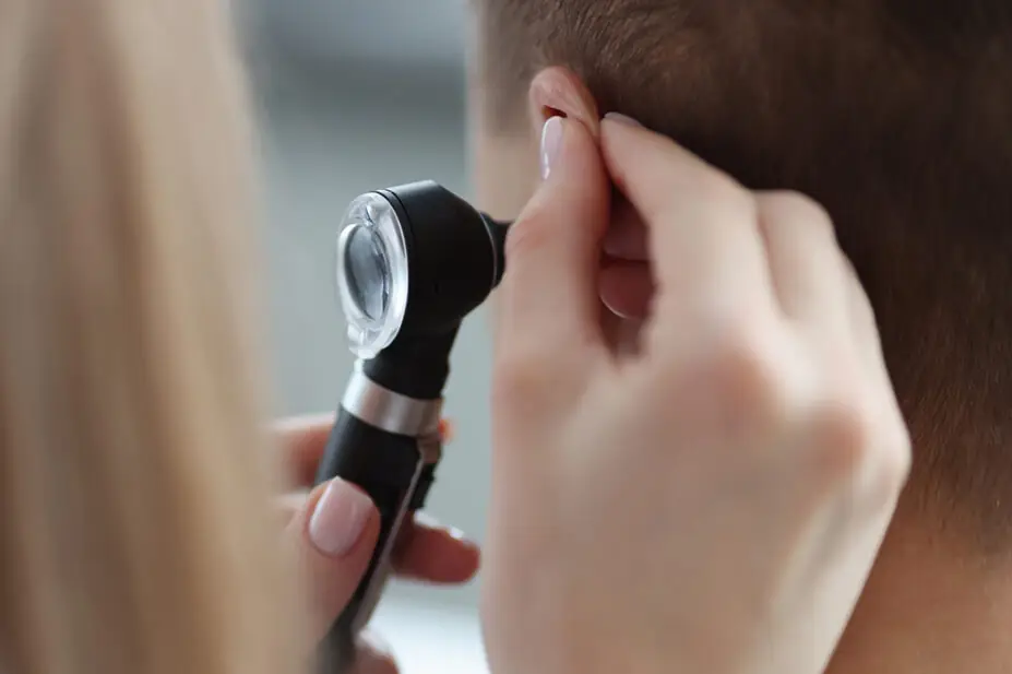 Pharmacist looking in someone's ear as part of Pharmacy First service