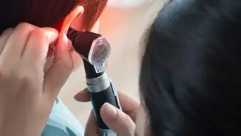 A pharmacist examining someone's ear