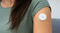 Close up of a glucose monitor on someone's arm