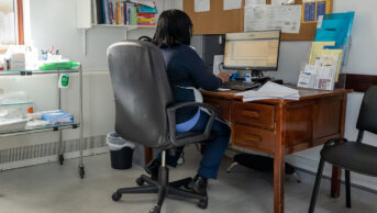 A GP working on a computer in consultation room