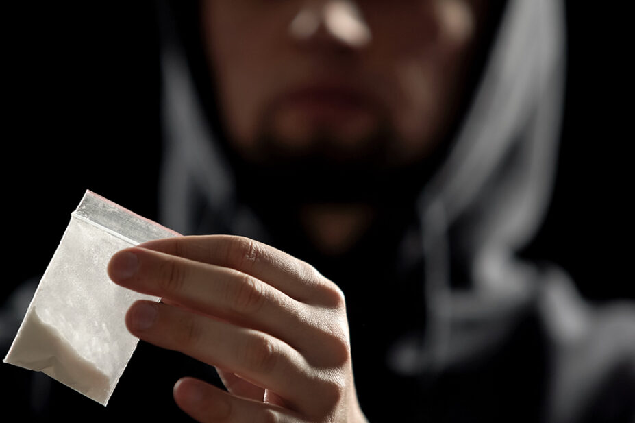 Someone holding white powder in bag, suggestive of illegal drugs