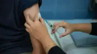 Doctor injects vaccine into patients arm