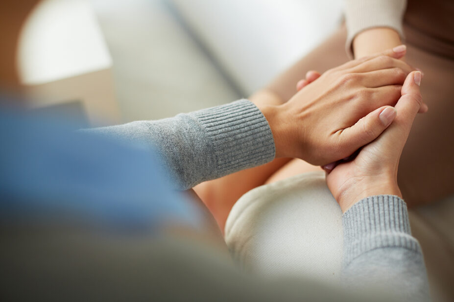 Close up of someone holding someone else's hands in support