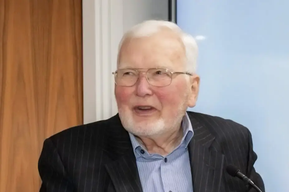 Photo of an older man with glasses, a short beard and white hair