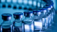 A group of vaccine bottles on a conveyor belt