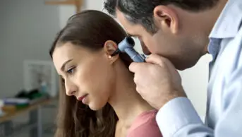 Woman has ear checked by healthcare professional