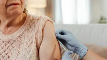 An older woman receives a vaccination from a healthcare professional