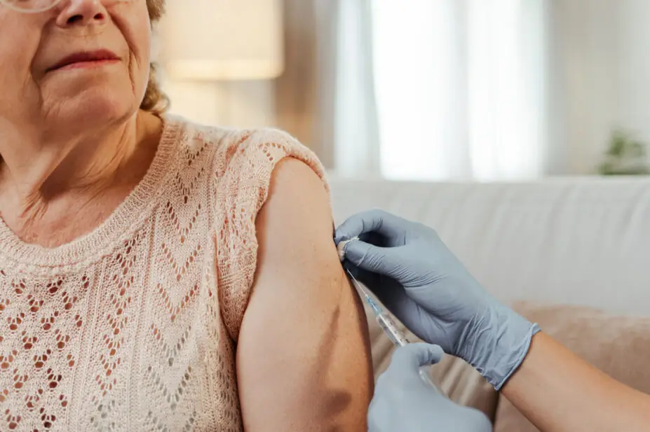 An older woman receives a vaccination from a healthcare professional