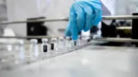 A group of vaccine bottles on a conveyor belt