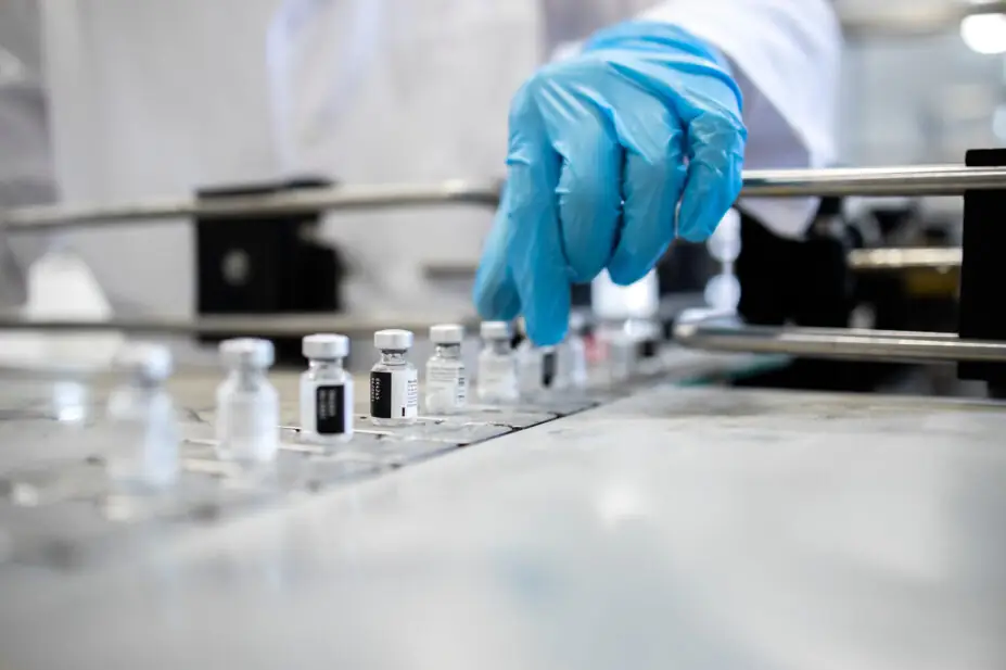 A group of vaccine bottles on a conveyor belt