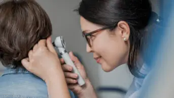 A GP examining boy's ear with otoscope