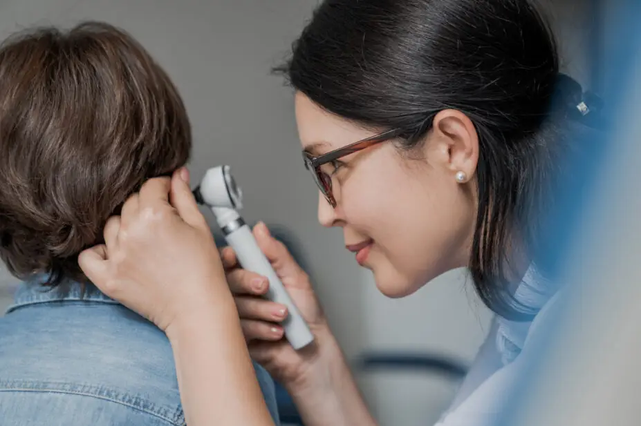 A GP examining boy's ear with otoscope