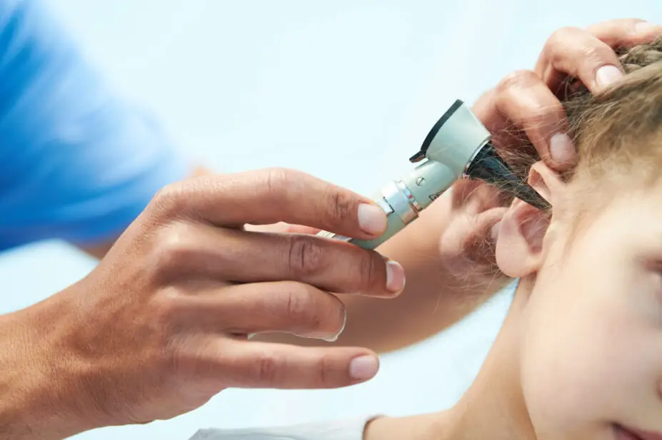 Healthcare professional examines patient's ear