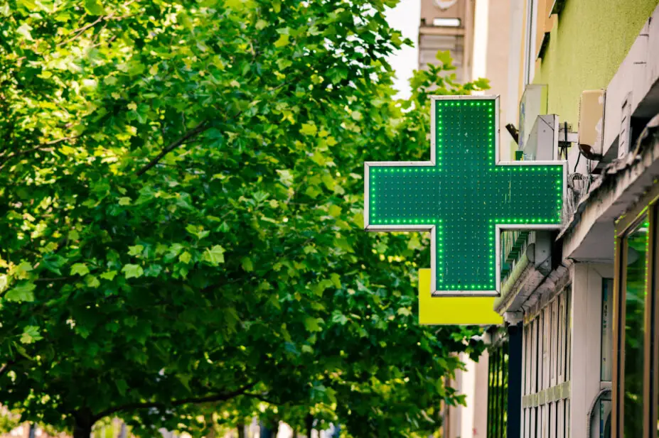 The green cross sign outside of a pharmacy