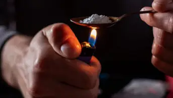 A drug user prepares drugs with a spoon and lighter