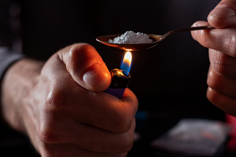 A drug user prepares drugs with a spoon and lighter