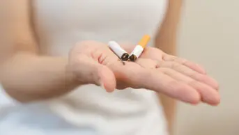 Young woman holding a broken cigarette in her hand