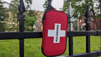 Naloxone kit box hanging on the fence in city urban area park