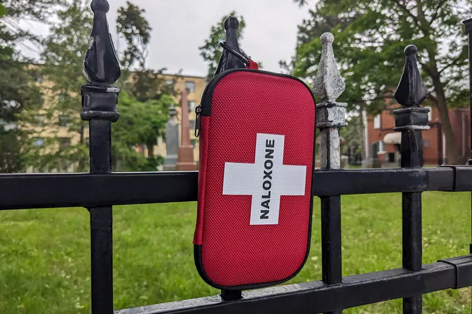 Naloxone kit box hanging on the fence in city urban area park