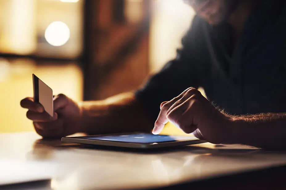 Man on tablet at home holding a credit card, suggesting online shopping concept