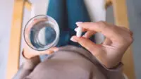 Woman holding glass of water and taking an antidepressant pill