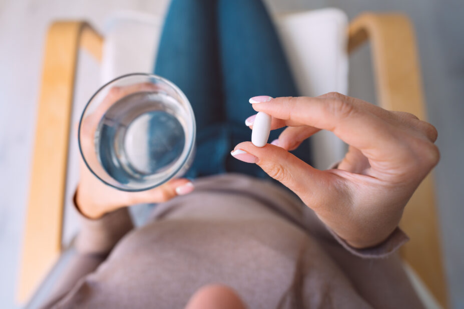 Woman holding glass of water and taking an antidepressant pill