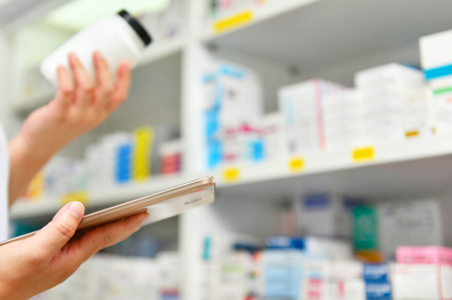 Pharmacist holds medicine bottle and computer tablet