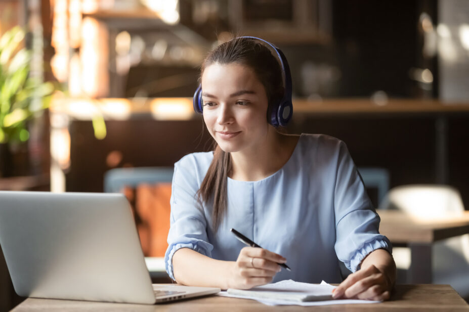 A woman taking notes while using a laptop