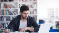 Student on laptop with text books