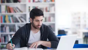 Student on laptop with text books