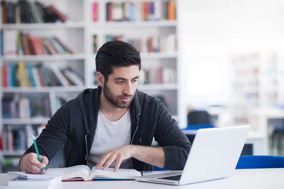 Student on laptop with text books