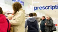 Busy pharmacy counter with lots of customers waiting