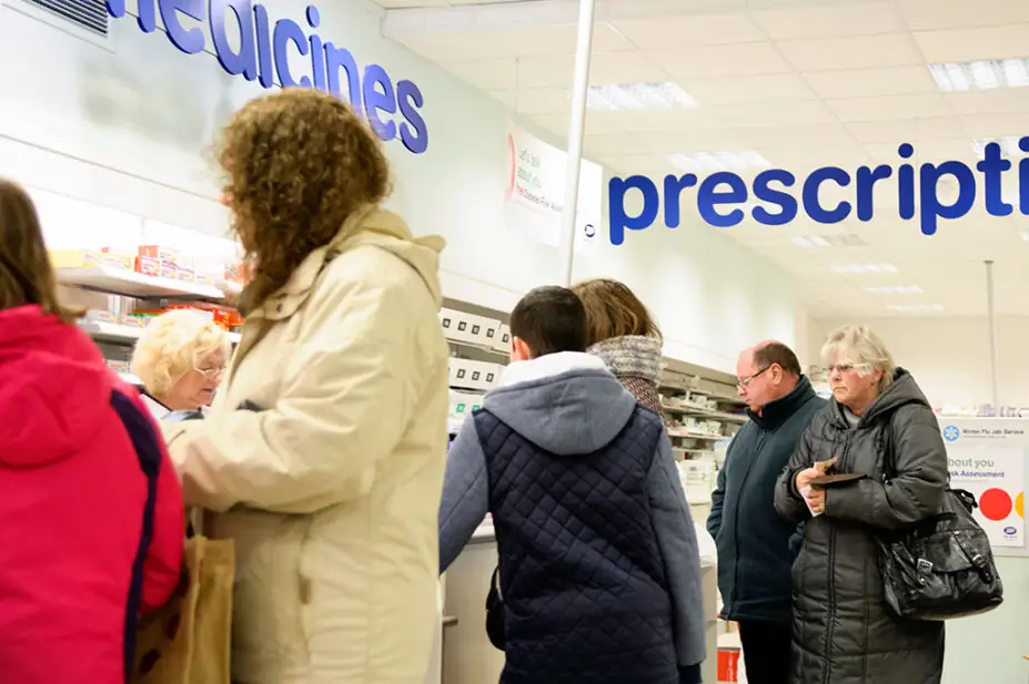 Busy pharmacy counter with lots of customers waiting