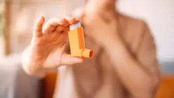 A woman suffering from asthma holds an inhaler