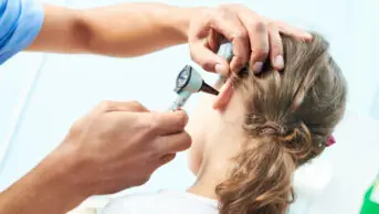 A healthcare professional examines a patient's ear