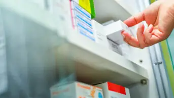 A pharmacist holds a box of medicine