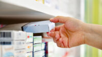 Close up of pharmacist's hand taking box of medicines off a shelf