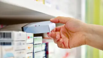 Close up of pharmacist's hand taking box of medicines off a shelf