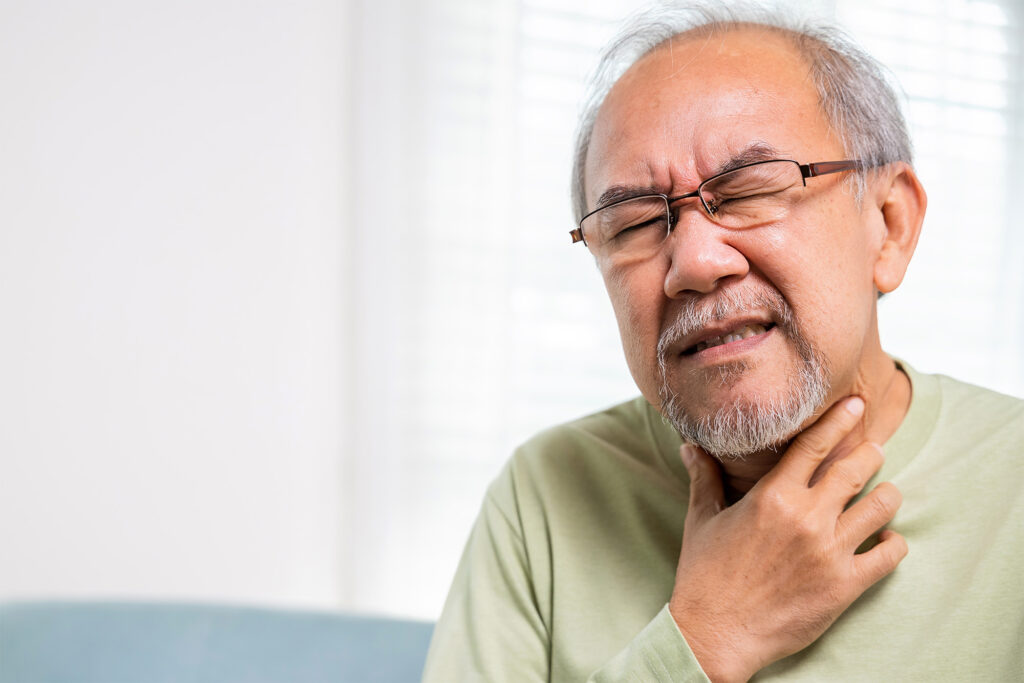 Photo of an older asian man clutching this throat 